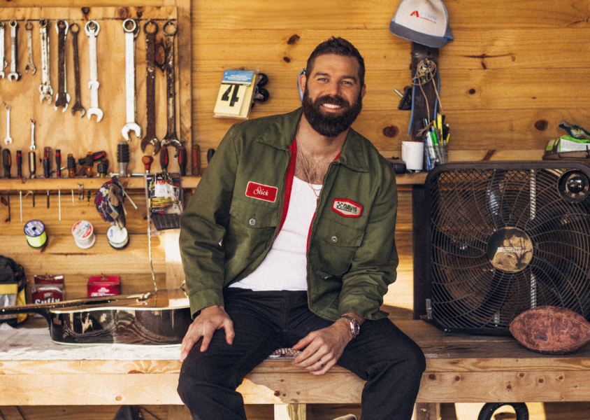 Man sitting on a workbench with tools behind him x